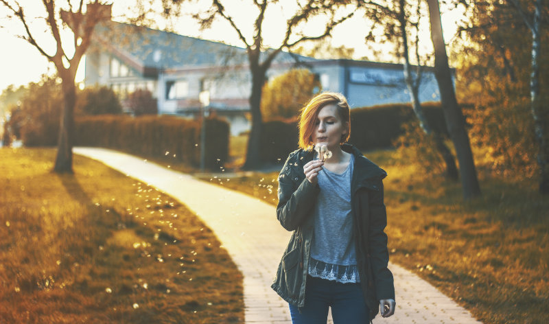 women blowing on a dandelion